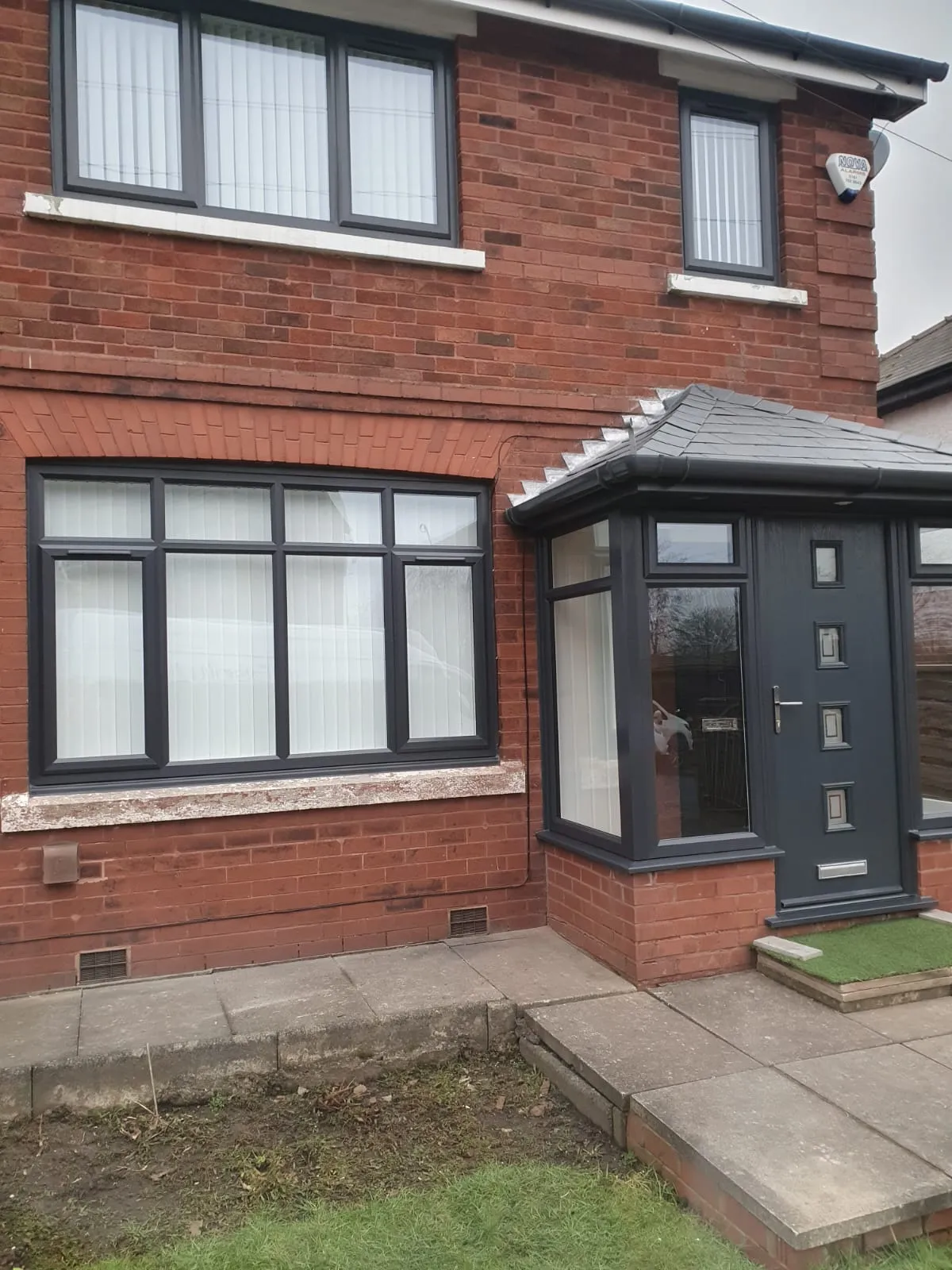 Anthracite grey PVC casement windows and porch on a red brick semi-detached home in Manchester