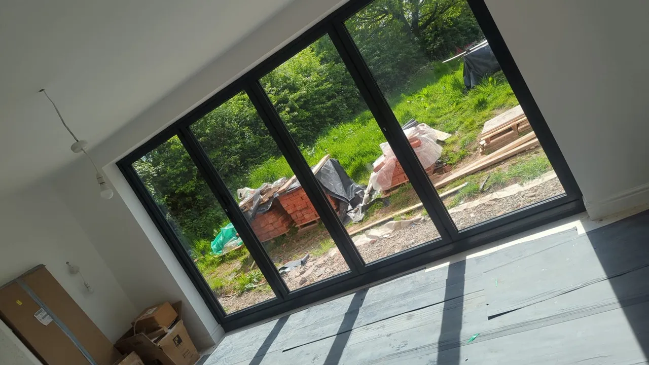 Black aluminium four-panel sliding doors viewed from inside a new-build room