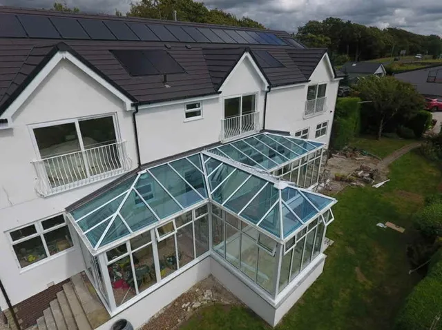 Aerial view of a large white PVC glass-roofed conservatory on a detached property