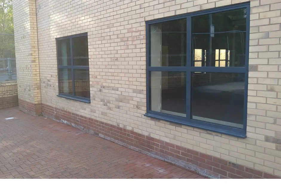 Grey aluminium commercial windows on a buff brick building in Greater Manchester