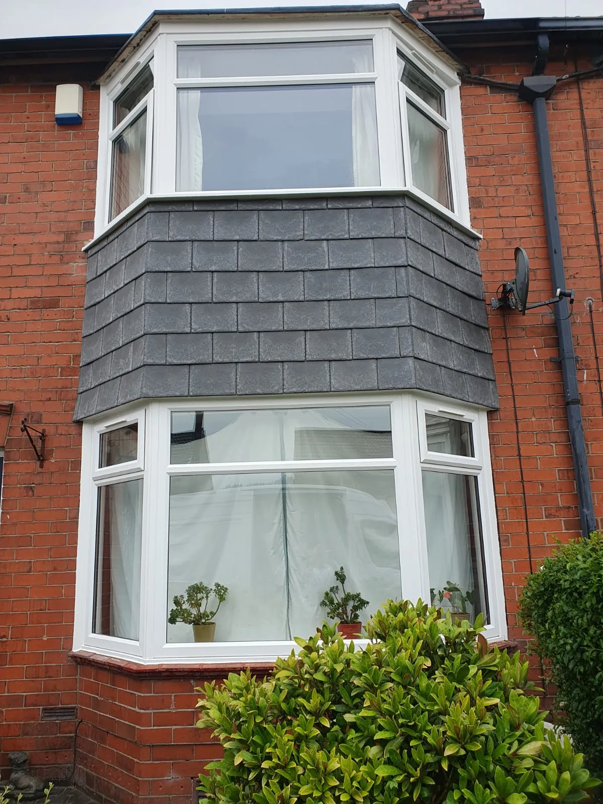 White PVC bay windows with slate cladding on a red brick terraced property
