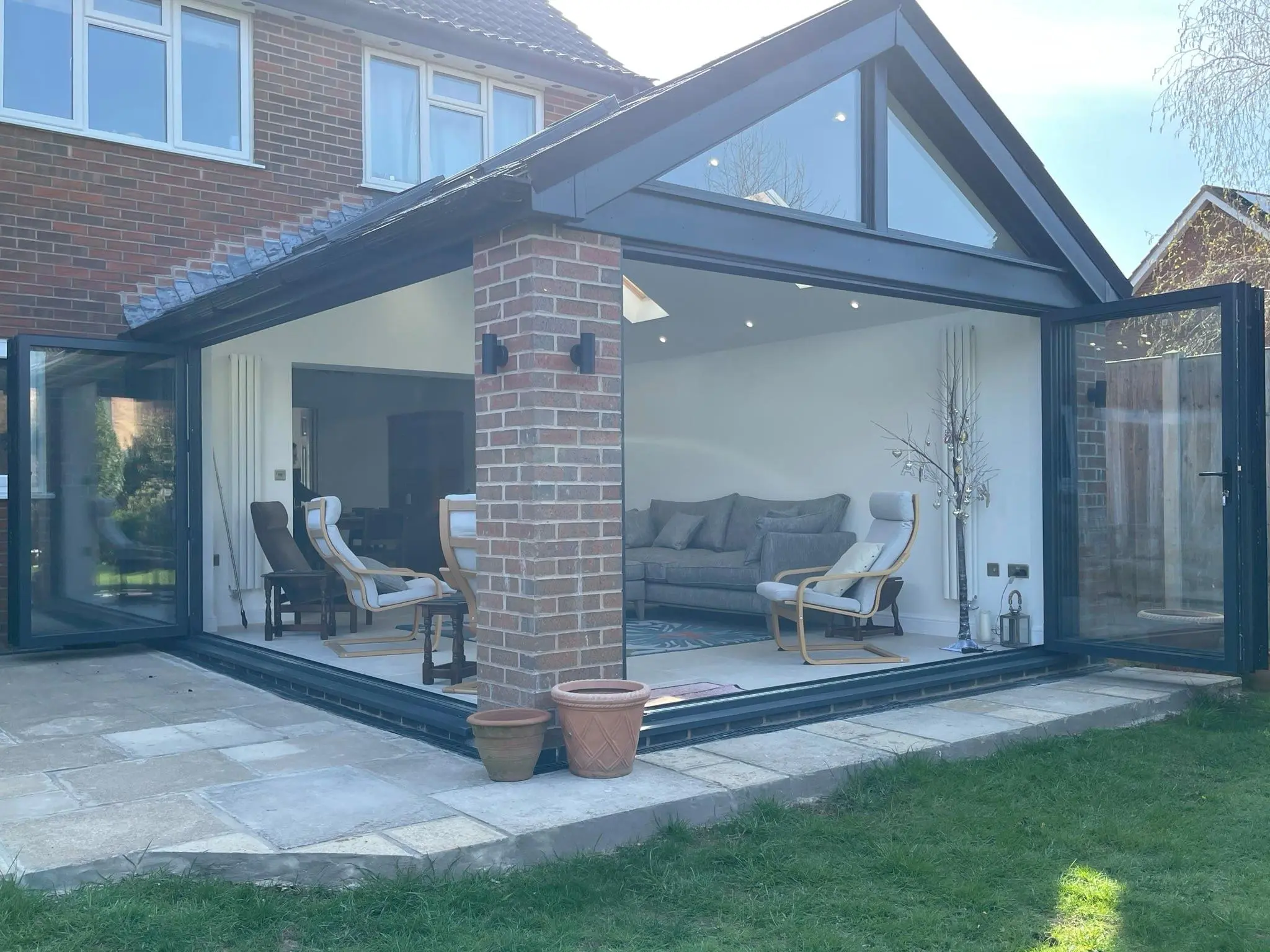 Grey aluminium gable-front orangery with open bifold doors and garden view